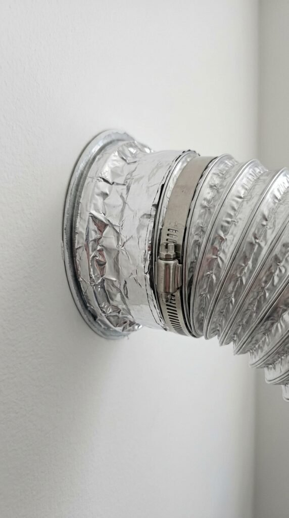 Connecting the dryer hose to the wall vent and sealing with foil tape